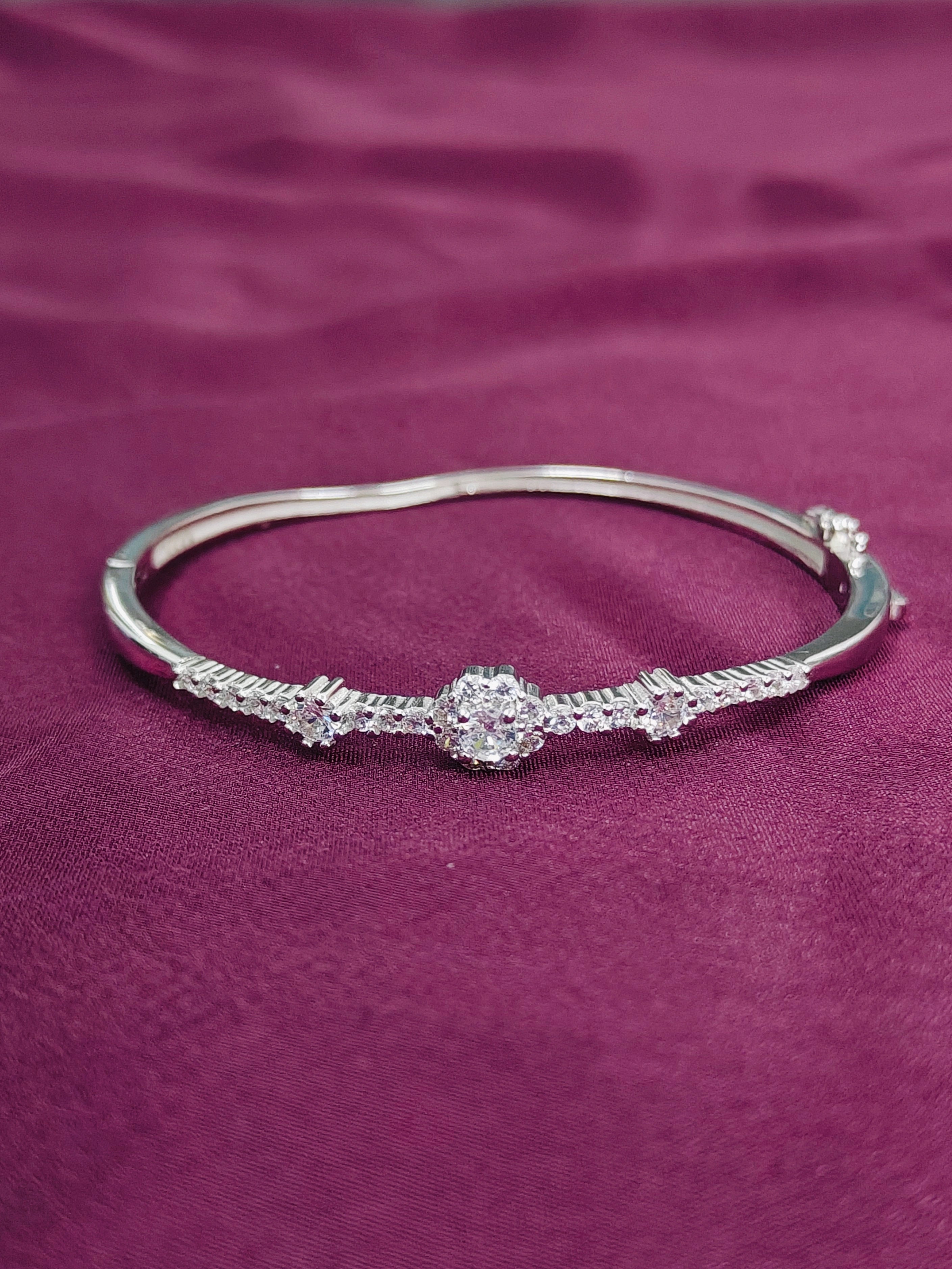 Silver bracelet with a central diamond on a purple fabric background
